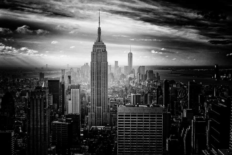 The Empire State Building stands tall over a black and white view of Manhattan from above.